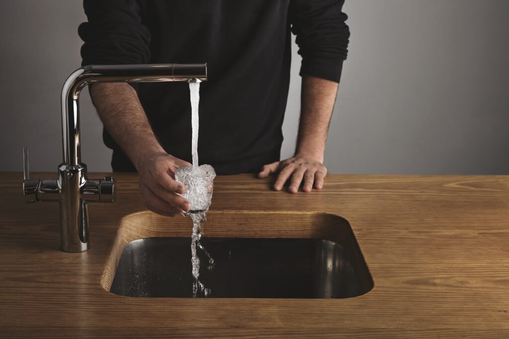 Barista rinses small glass with tap water