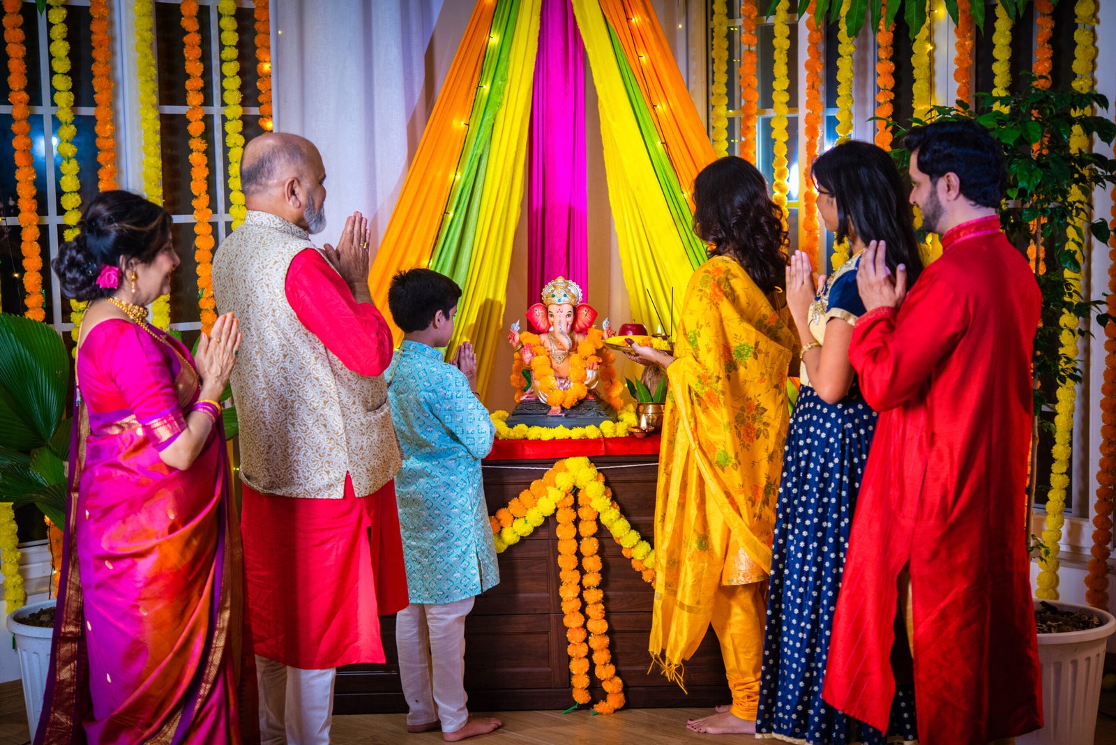 Indian family in traditional wear performing Ganesh Puja or Aarti at home, a religious ritual