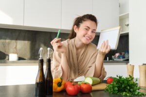 goodlooking-smiling-Girl with grocery list holding notebook reading recipe cooking