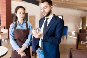 Frowning restaurateur checking wineglass