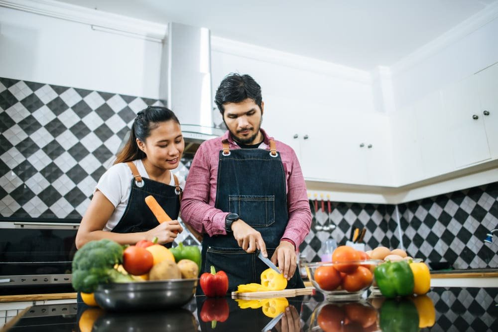 Happy young couple help each other chopping vegetable preparing for cooking 