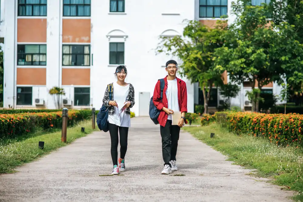 Male and female students wear a face chill and stand in front of the university