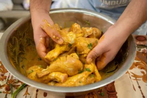 A man mixing a chicken with a spices