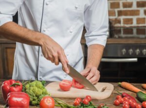  Chef's hand cutting the ripe tomato 