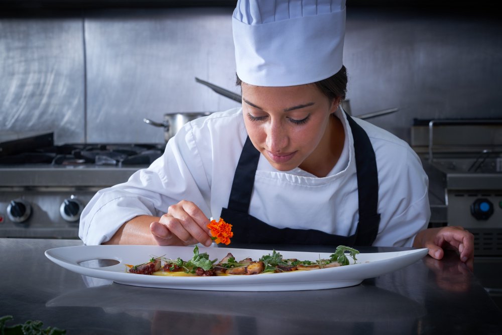 Chef woman garnishing flower in dish