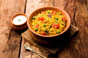 A bowl of rice with a green leaf and black beans