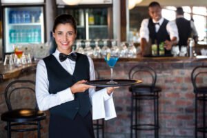 
Portrait of bartender holding serving tray with glass of cocktail